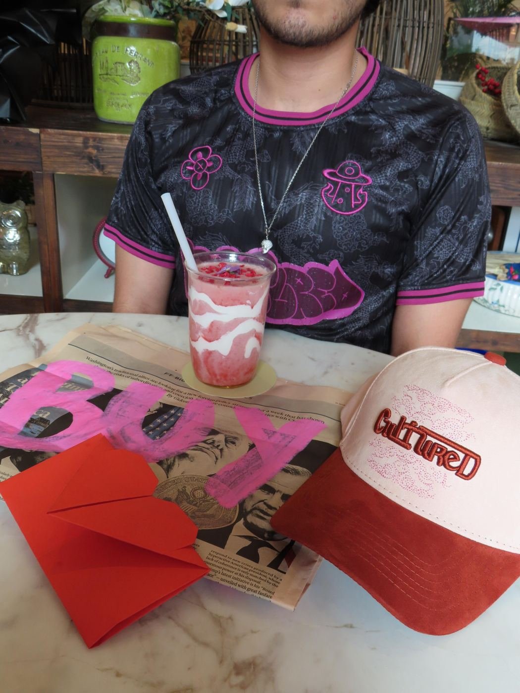 Cultured Apparel lookbook — slow morning in a Dubai cafe wearing the Summer Archive tee